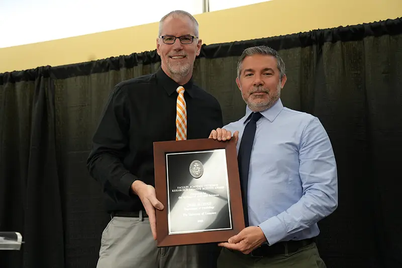 Chris Elledge is presented with an award by Todd Moore at the 2023 Faculty Awards Convocation