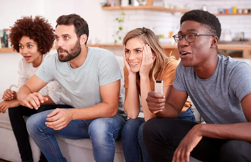 A group of friends sitting on the couch watching tv